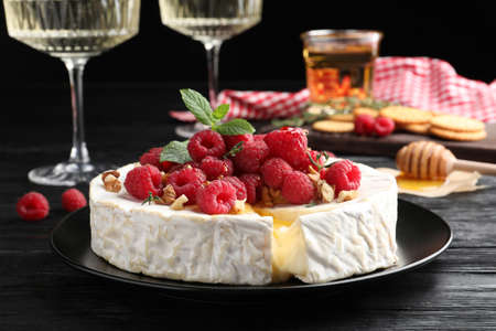 Brie cheese served with raspberries and walnuts on black wooden tableの写真素材