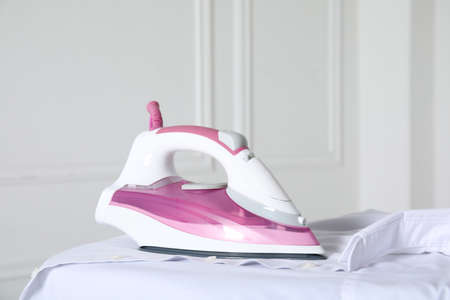 Modern iron and clean shirt on board indoorsの写真素材
