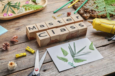 Master class in handmade craft. Composition with cubes and supplies on wooden table