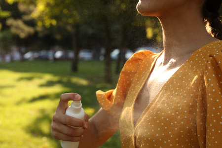 Woman applying insect repellent onto neck in park, closeupの写真素材