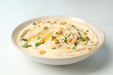 Tasty hummus with garnish in bowl on white table, closeupの写真素材