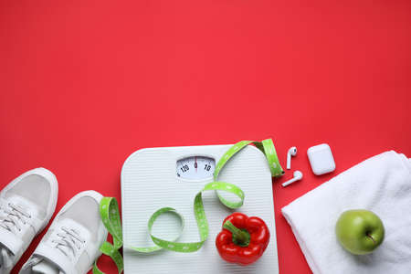Flat lay composition with scales and measuring tape on red background, space for textの写真素材
