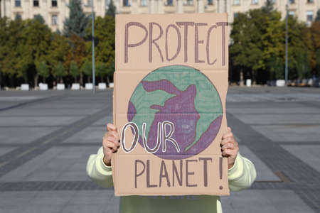 Woman with poster protesting against climate change on city streetの写真素材