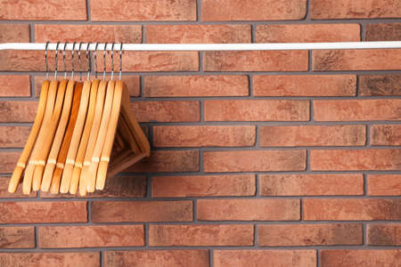 Wooden clothes hangers on rail near red brick wall. Space for textの写真素材