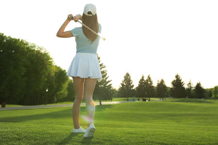 Woman playing golf on green course, back view. Space for textの写真素材