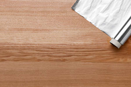 Roll of aluminum foil on wooden table, top view. Space for textの写真素材