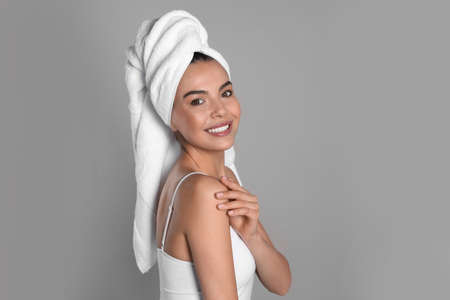 Beautiful young woman with towel on head against gray backgroundの写真素材
