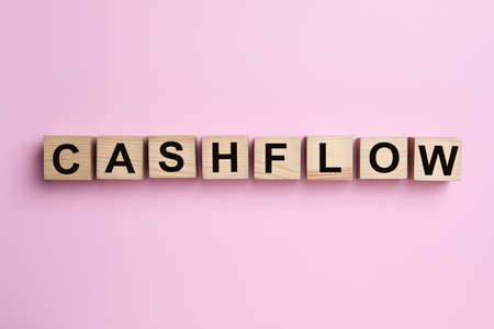Wooden cubes with phrase Cash FLow on pink background, flat layの写真素材