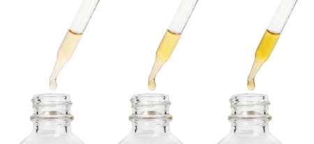 Dripping essential oils from pipettes into glass bottle on white background, collage. banner designの写真素材