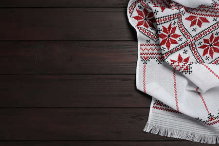 Beautiful rushnyk on wooden table, top view with space for text. Ukrainian national embroidery