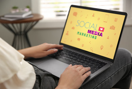 SMM (Social Media Marketing) concept. Woman working with modern laptop indoors, closeupの写真素材