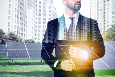 Double exposure of businessman and solar panels installed outdoors. alternative energy sourcesの写真素材