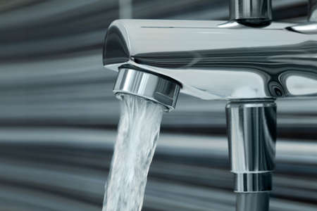 Water flowing from bath tap on blurred background, closeupの写真素材