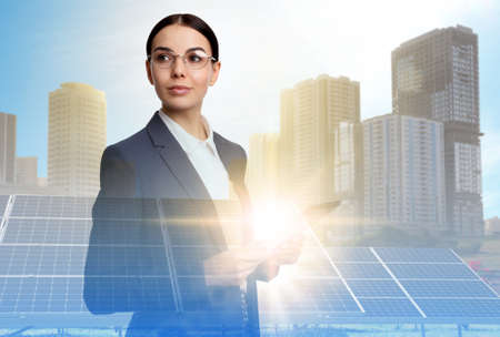 Double exposure of businesswoman with tablet and solar panels installed outdoors. alternative energy sourcesの写真素材