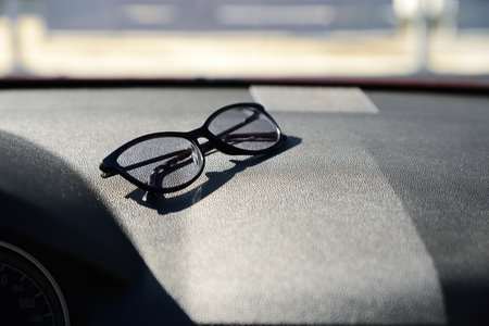 Stylish glasses on dashboard in car, space for textの写真素材