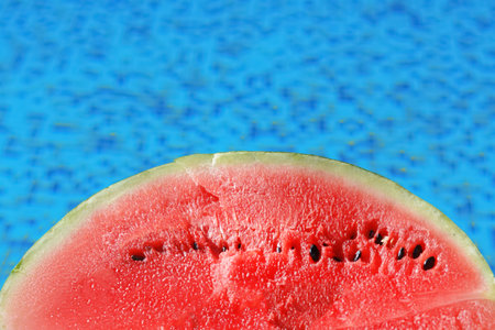 Half of fresh juicy watermelon near swimming pool outdoors, closeup. Space for text