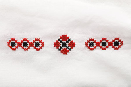 Beautiful red Ukrainian national embroidery on white fabric, top view