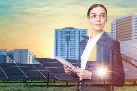 Double exposure of businesswoman with tablet and solar panels installed outdoors. alternative energy sourcesの写真素材
