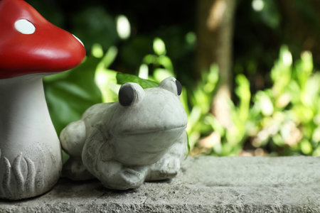 Frog figure and decorative fly agaric on stone parapet outdoors. Space for textの写真素材