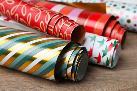 Different colorful wrapping paper rolls on wooden table, closeupの写真素材
