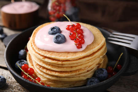 Tasty pancakes with natural yogurt, blueberries and red currants on wooden table, closeupの写真素材