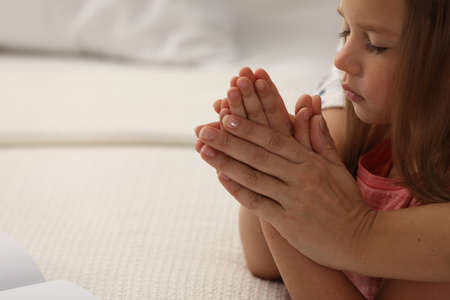 Mature woman with her little granddaughter praying together indoors, closeup. Space for textの写真素材