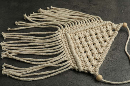 Stylish beige macrame on gray table, closeup