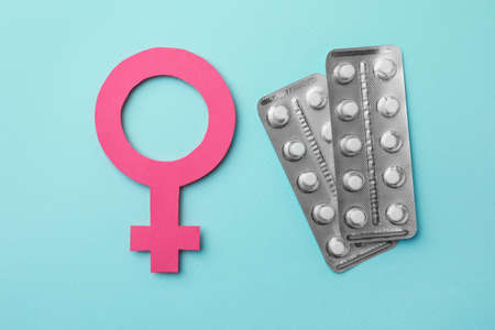 Female gender sign and blisters of pills on turquoise background, flat lay. Women's health conceptの写真素材