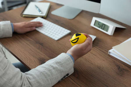 Man with antistress ball at desk in office, closeup