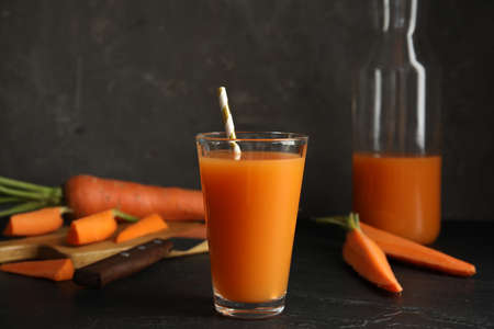 Glass of freshly made carrot juice on black tableの写真素材