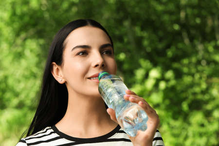 Young woman drinking water outdoors. Refreshing drinks