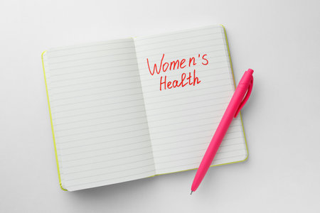 Notebook with words Women's Health and pen on white background, top viewの写真素材
