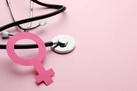 Female gender sign and stethoscope on pink background, closeup. Space for textの写真素材