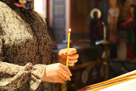 Mature woman holding candle in church, closeup