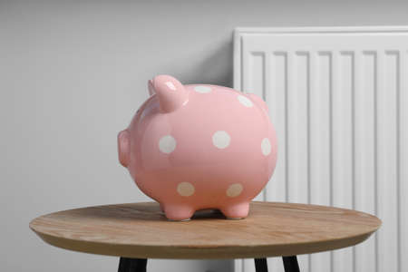 Piggy bank on wooden table near heating radiatorの写真素材