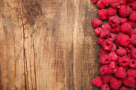 Fresh ripe raspberries on wooden table, flat lay. Space for text