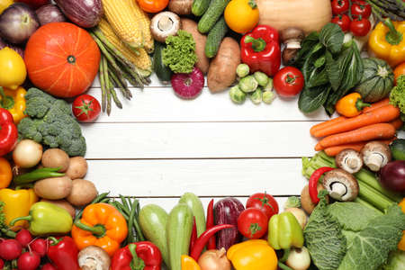 Frame of different fresh vegetables on white wooden table, flat lay. Space for text