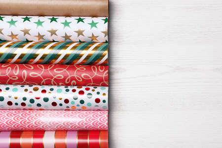 Different colorful wrapping paper rolls on white wooden table, flat lay. Space for textの写真素材