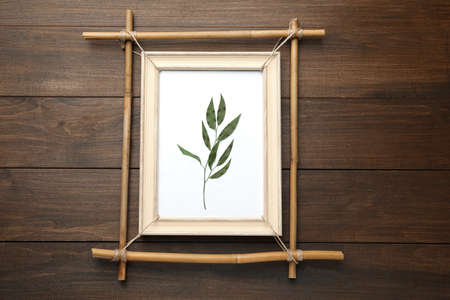 Bamboo frame with dried plant on wooden table, top viewの写真素材