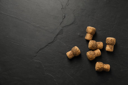 Sparkling wine corks with grape images on black table, flat lay. Space for textの写真素材