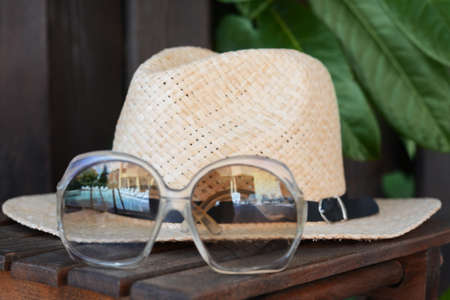Stylish hat and sunglasses on wooden table, closeup. beach accessoriesの写真素材