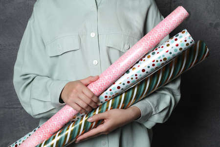 Woman holding different colorful wrapping paper rolls on gray background, closeupの写真素材