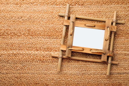 Empty bamboo frame on wicker straw background, top view. Space for textの写真素材