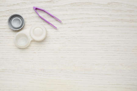 Case with contact lenses and tweezers on white wooden table, flat lay. Space for textの写真素材