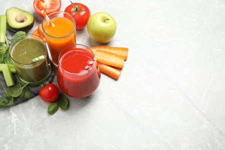 Delicious vegetable juices and fresh ingredients on light gray table. Space for textの写真素材