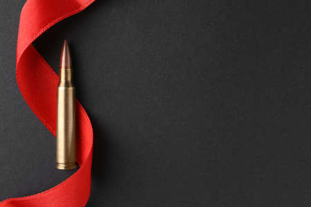 Bullet and red ribbon on black background, top view. Space for text