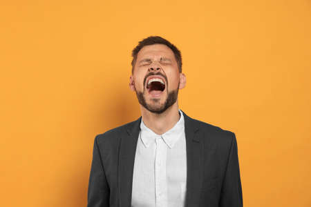 Aggressive man shouting on orange background. hate conceptの写真素材