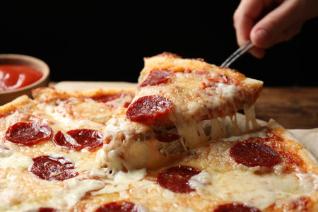 Woman taking slice of tasty pepperoni pizza at table, closeupの写真素材