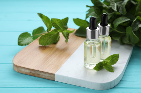 Bottles of essential oil and mint on turquoise wooden tableの写真素材