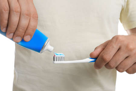 Man applying toothpaste on brush against white background, closeup